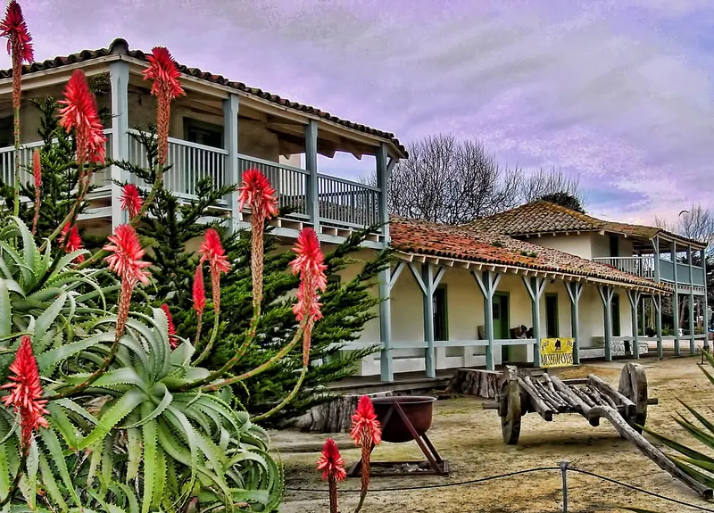 The adobe Custom House in Monterey State Historic Park, with red aloe flowers in front