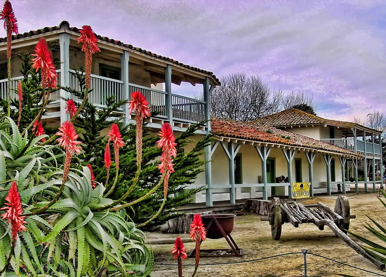 The adobe Custom House in Monterey State Historic Park, with red aloe flowers in front